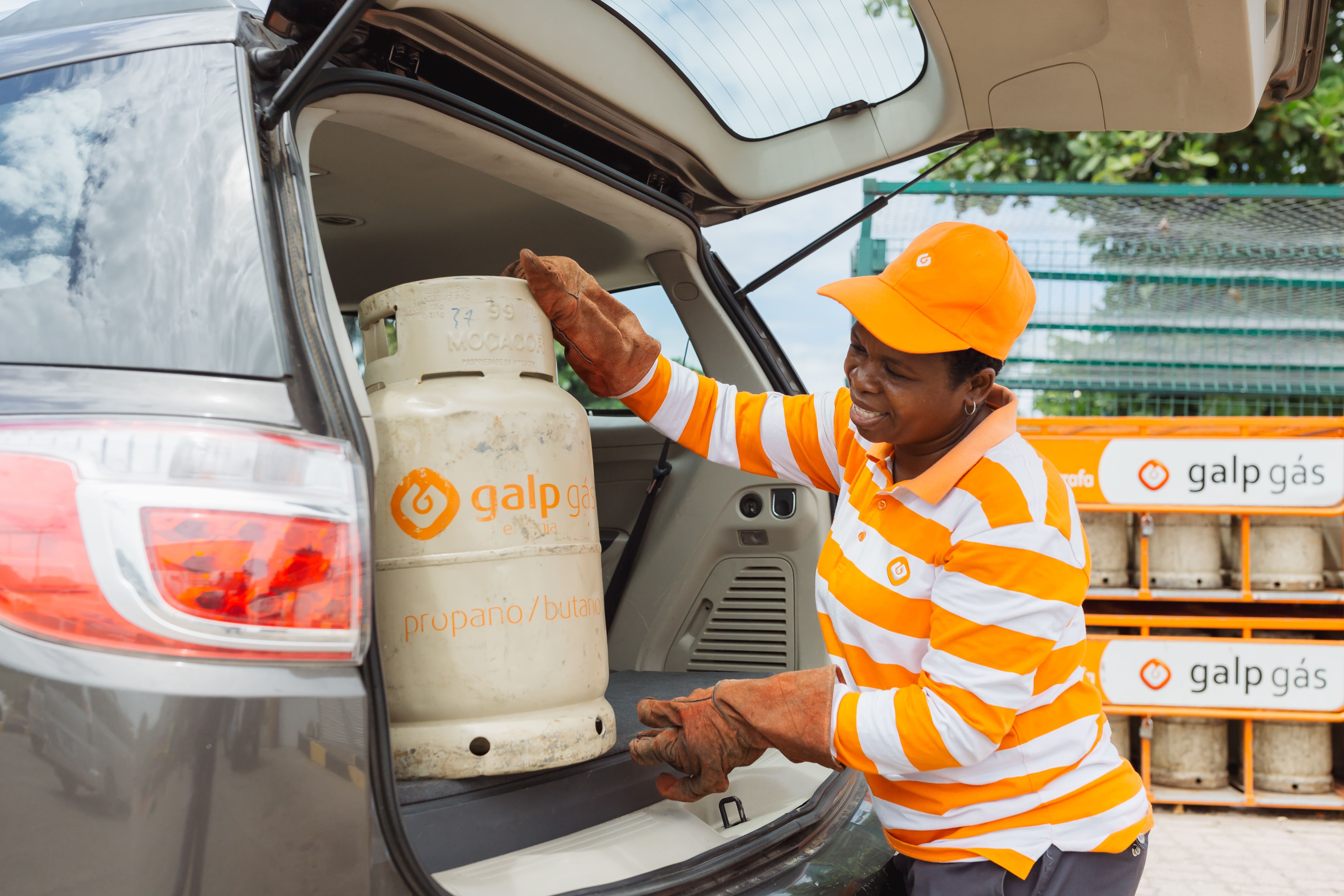 Funcionário da Galp a colocar uma bilha de gás na bagageira de um carro.
