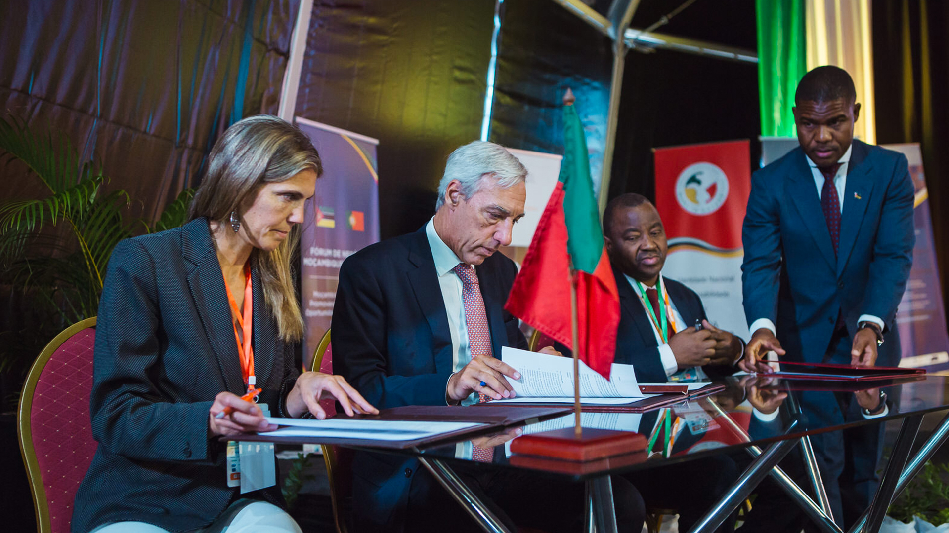 Fotografia de quatro pessoas sentadas a uma mesa. Todas estão a mexer em pastas e papéis.