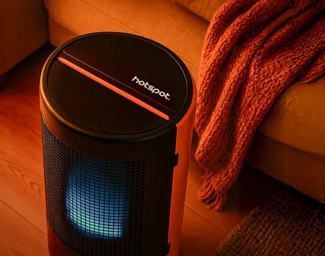 Fotografia de um aquecedor interior Galp numa sala. É visível um sofá com uma manta atrás do aquecedor.