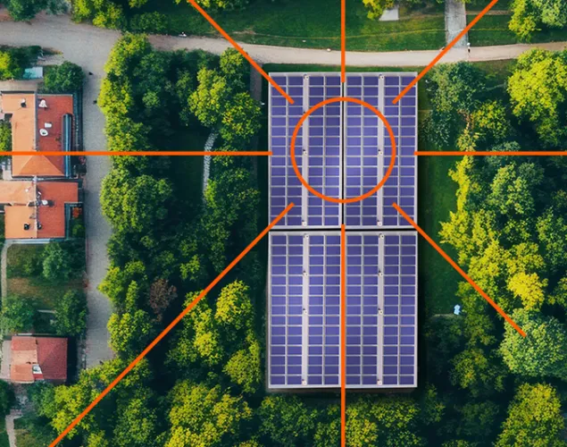 Fotografia de uma vila vista de cima. Vêm-se telhados, árvores e painéis solares no meio das árvores.