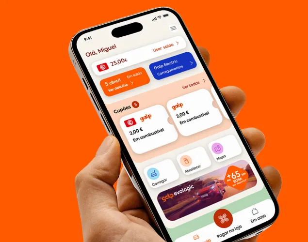 Smartphone segurado na mão com a app Mundo Galp aberta, apresentado sobre fundo laranja, com destaque para saldo, cupões e benefícios em combustível e carregamentos.