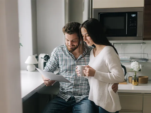Casal em casa a analisar uma factura de energia, com chávenas nas mãos, representando um consumidor a gerir os seus consumos energéticos.