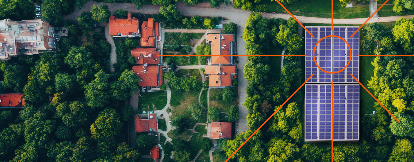 Fotografia de uma vila vista de cima. Vêm-se telhados, árvores e painéis solares no meio das árvores.