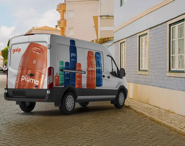 Fotografia de uma carrinha de caixa fechada, com as várias garrafas de gás viniladas na carrinha. A mesma está parada numa rua.