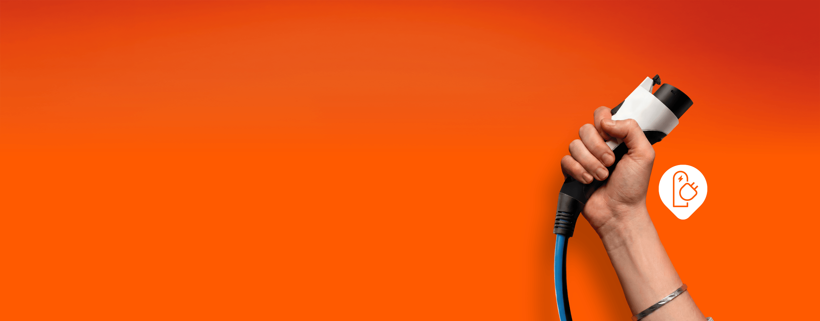 **Descrição breve:** Mão segura um conector de carregamento para veículo elétrico sobre fundo laranja.